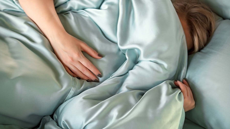 Woman wrapped in a green duvet cover in TENCEL™ Lyocell.