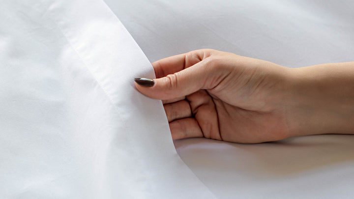 Woman touching a white Egyptian Cotton™ Percale Flat Sheet.