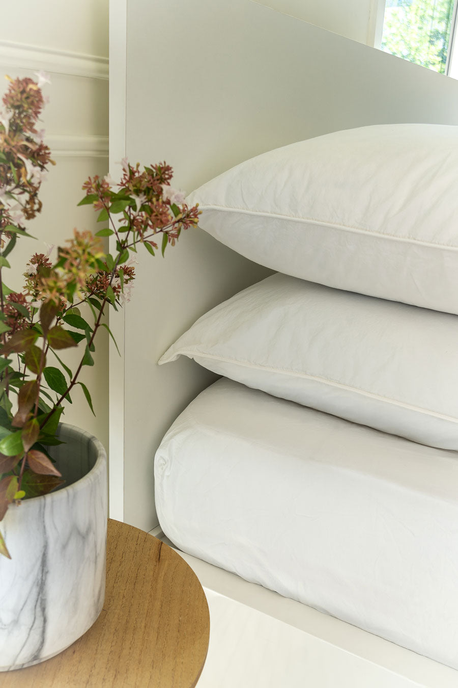 Detail of the corner of the bed with two white pillowcases and a white Organic Cotton Percale fitted sheet.