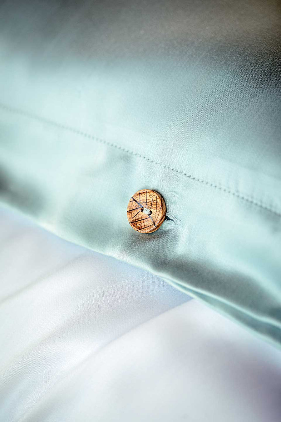 Olive button detail on a green TENCEL™ Lyocell Sateen duvet cover from THON.