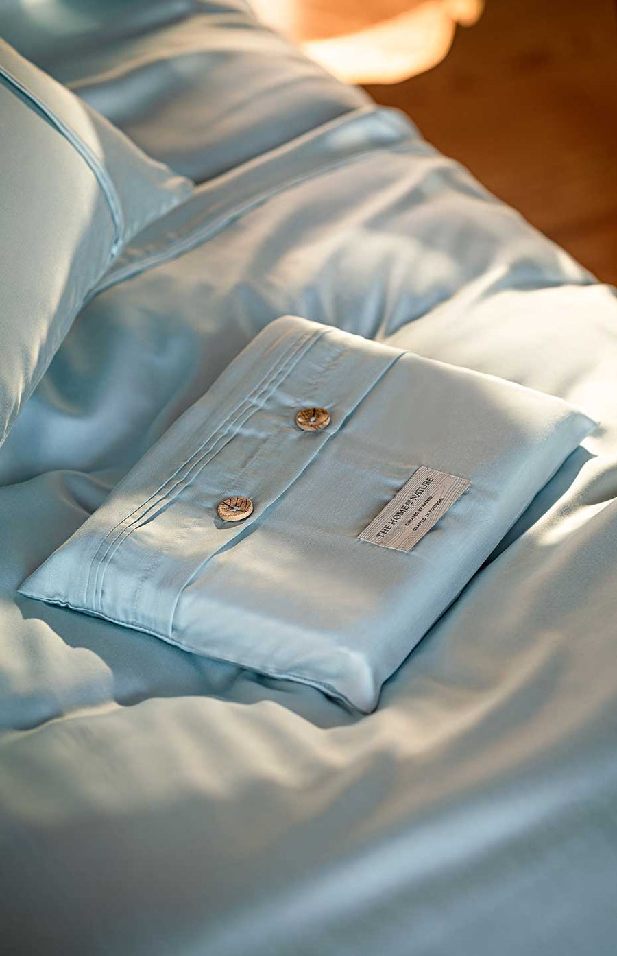 White eco-friendly packaging in TENCEL™ Lyocell from THON on top of a serene mint duvet cover.