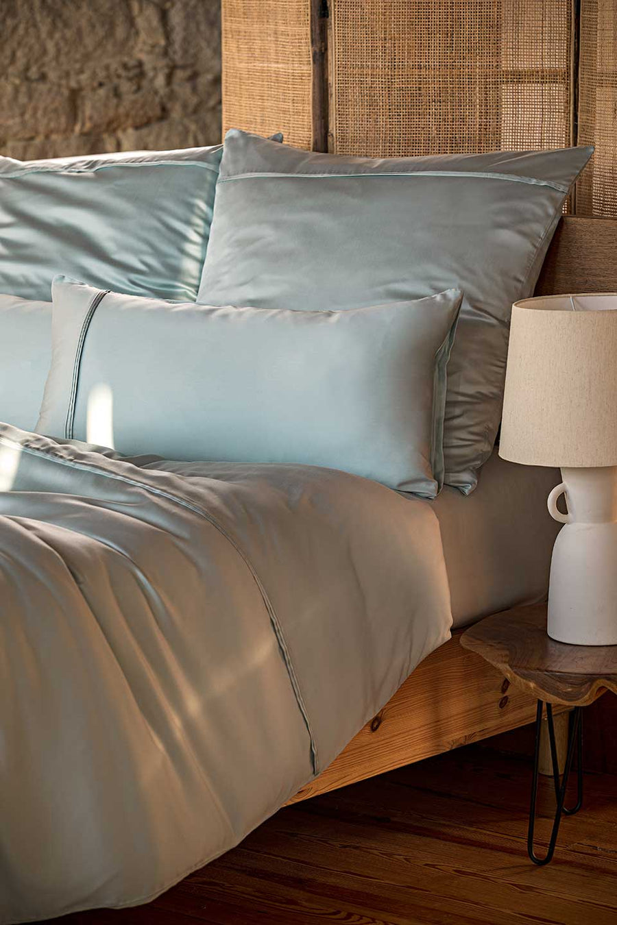 Bed with TENCEL™ Lyocell bedding next to an rustic bedside table.