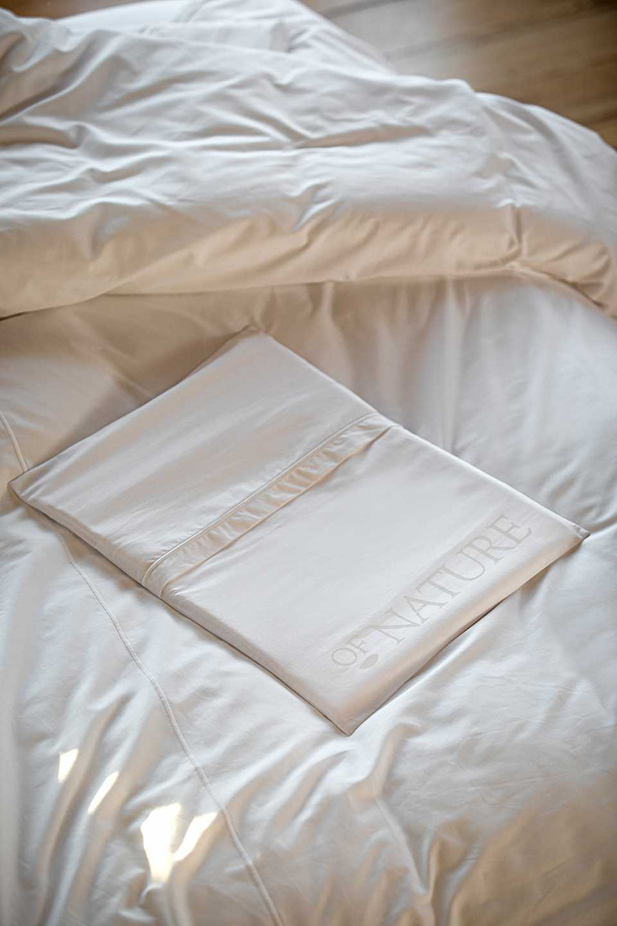 White eco-friendly packaging in Egyptian Cotton™ Percale from THON on top of a gray duvet cover.