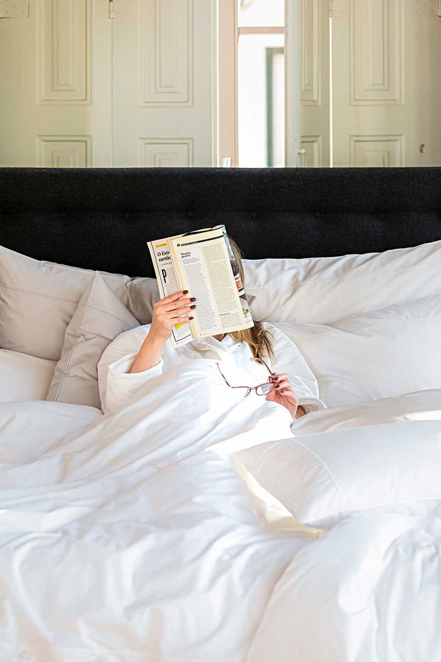 Woman reading a magazine while lying on a bed with a white duvet cover and pillowcase in Egyptian Cotton™ Percale.