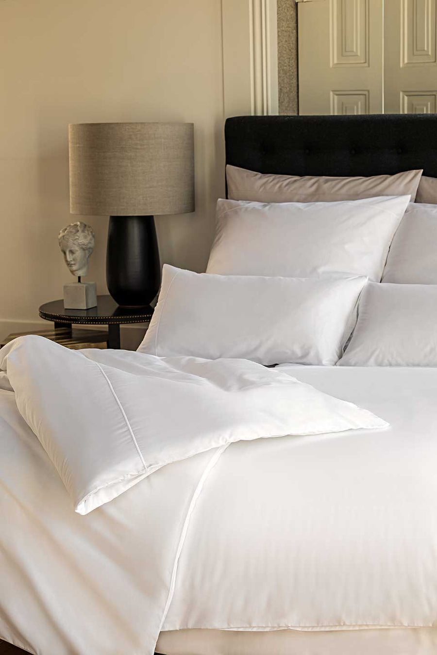 Bed with Egyptian Cotton™ Percale bedding next to an elegant bedside table.