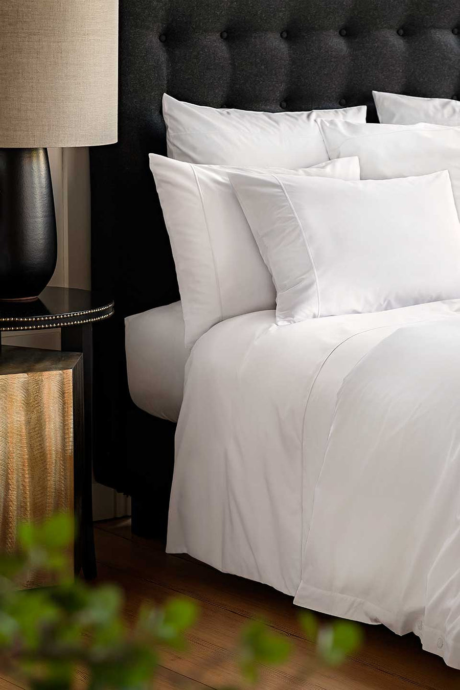 Bed with white Egyptian Cotton™ Percale bedding next to an elegant bedside table.