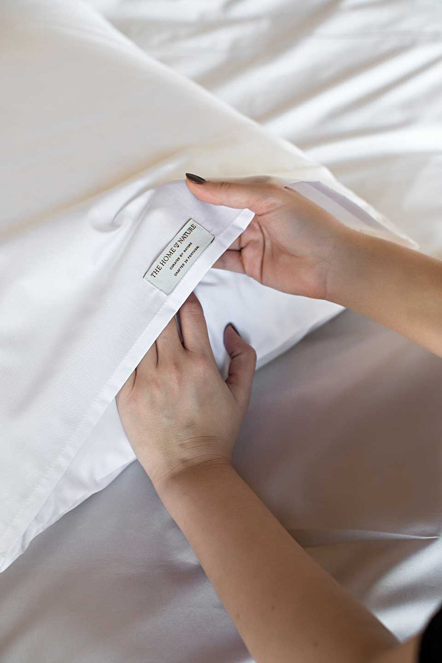 Woman putting a pillow on a white pillowcase from THON.