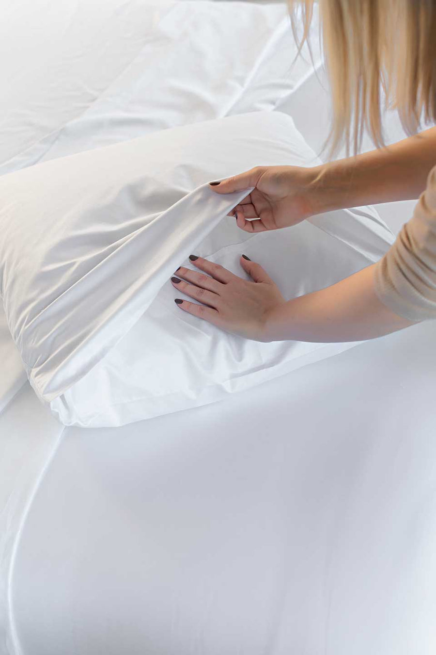 Woman placing a pillow on a white Egyptian Cotton™ Sateen pillowcase.