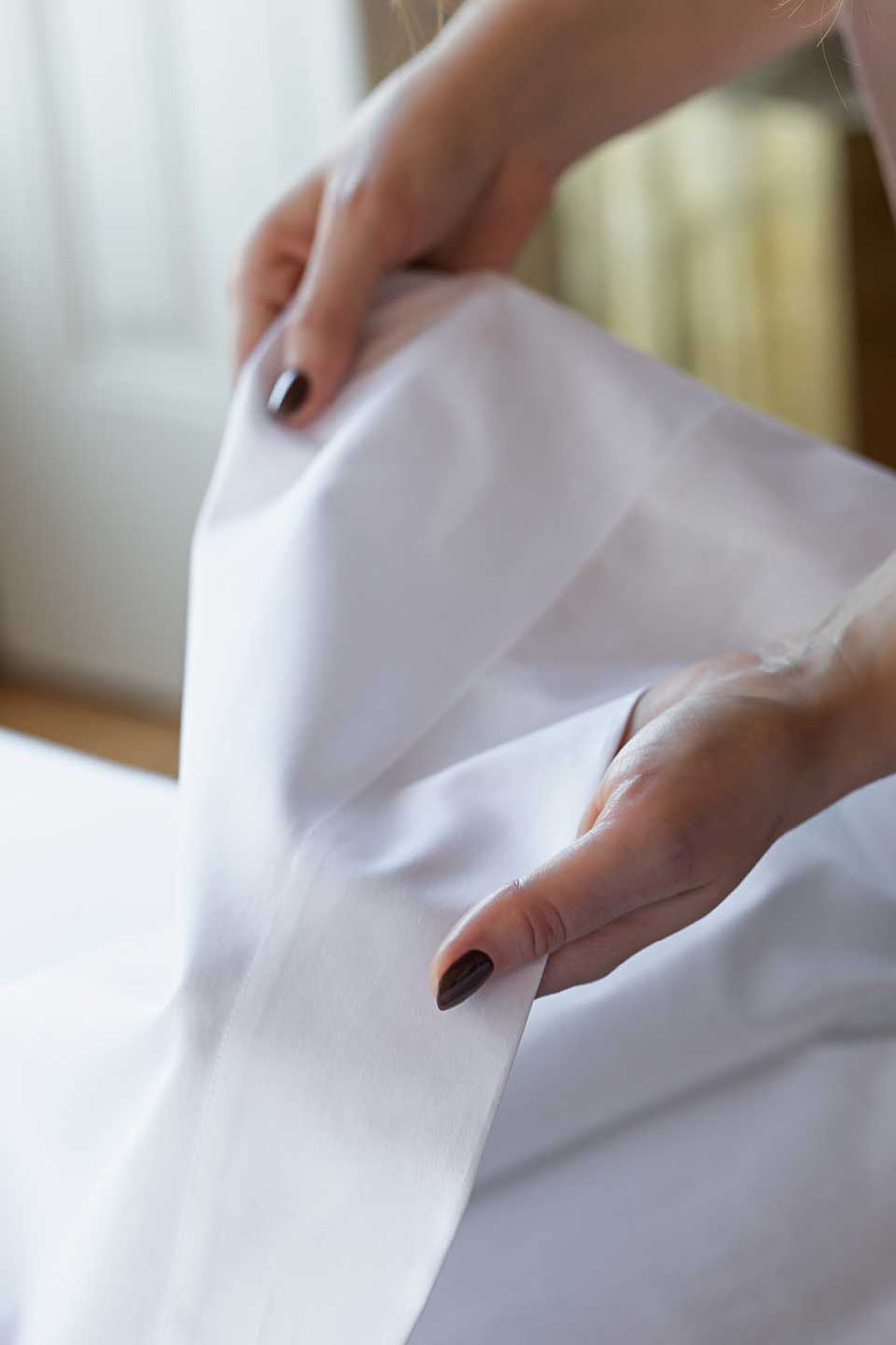 Woman touching a white Egyptian Cotton™ Sateen flat sheet from THON.